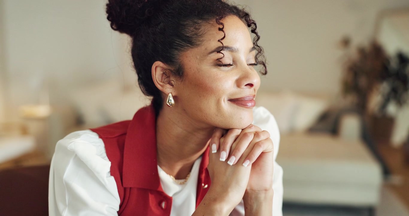 Thoughtful Young Woman Resting Chin on Hands in Bright Living Room