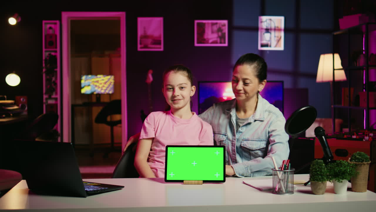 Figlia sorridente che filma contenuti online con i suoi genitori utilizzando il tablet con schermo verde dello sponsor