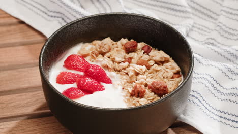 hands preparing a delicious yogurt parfait with granola, strawberries, and blueberries.