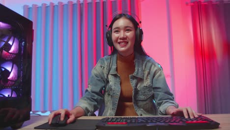 excited asian girl gamer celebrates victory while playing video game on computer