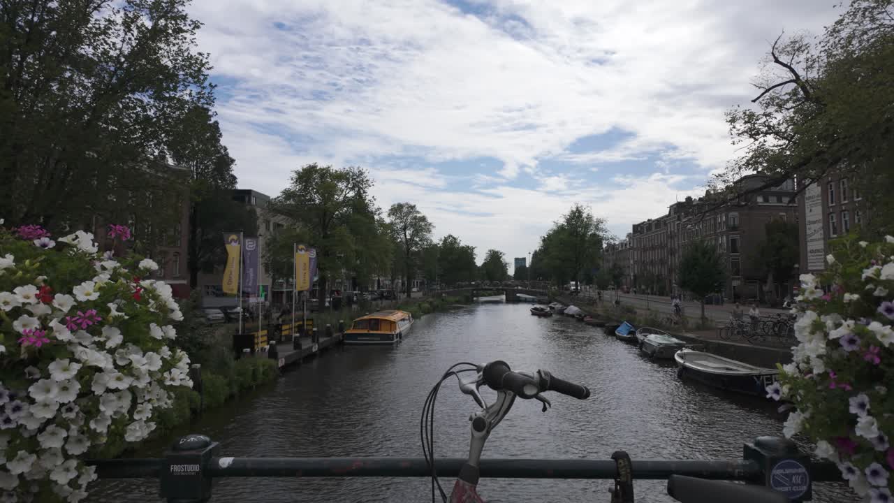 Scenic view from Amsterdam bridge of canal, flowers, and historic city architecture