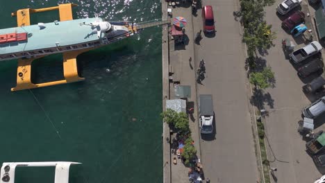 Overhead-shot-of-passenger-boats-docked-at-the-seaport-while-loading-and-unloading-travelers,-aerial-top-down