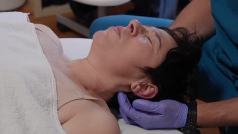 closeup of a woman lying on her back with a hand supporting her neck during therapy