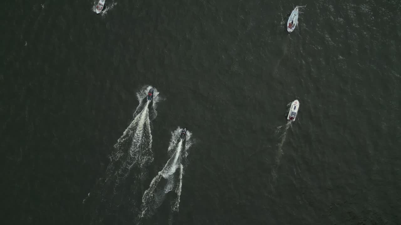 Two boats sailing on calm, dark water captured from an aerial view