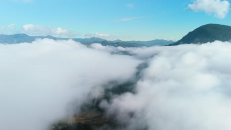 Über-Dem-Wolkenzeitraffer-öffnen-Sich-Wolken-über-Dem-Gebirgstal,-Wolken-Verschwinden,-Dicke-Wolkenschichten-öffnen-Sich,-Blauer-Himmel,-Berghintergrund,-Luftdrohne