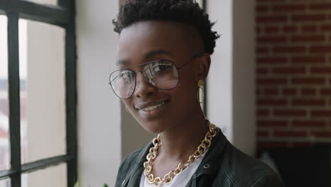 Retrato-Elegante-Joven-Afroamericana-Estudiante-Sonriendo-Feliz-Disfrutando-De-Un-Estilo-De-Vida-Exitoso-Usando-Gafas-De-Moda-Mirando-Por-La-Ventana-En-Un-Moderno-Apartamento-Loft