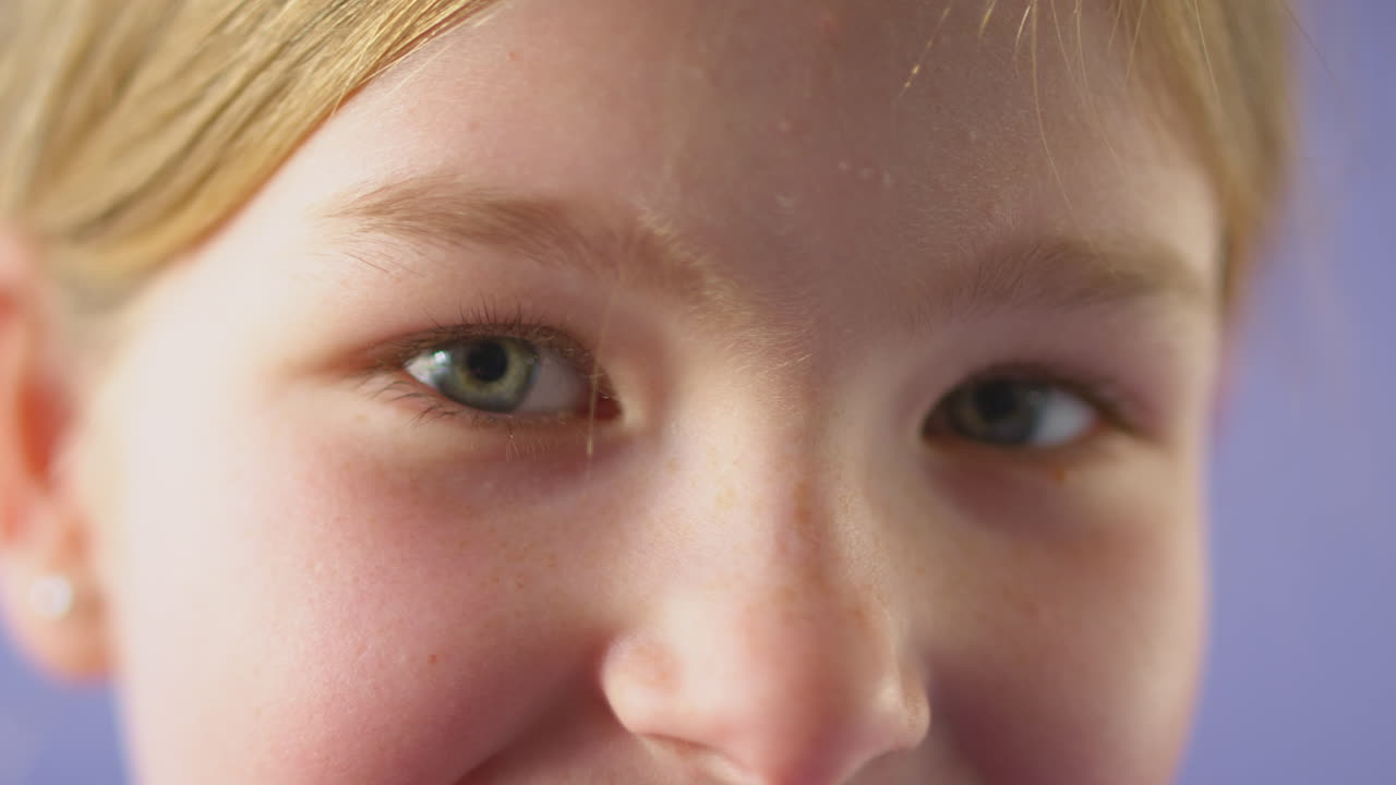 보라색 바탕에 긴 머리카락을 가진 웃는 소녀의 클로즈업 스튜디오 초상화