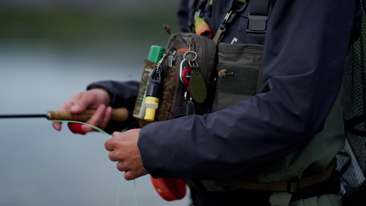 Close-up peralatan dan tangan seorang pemuda yang sedang melempar joran fly fishing