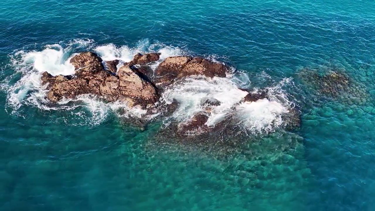 Ripresa aerea con drone di onde turchesi dell'Oceano Pacifico che si infrangono contro rocce scure in Australia.