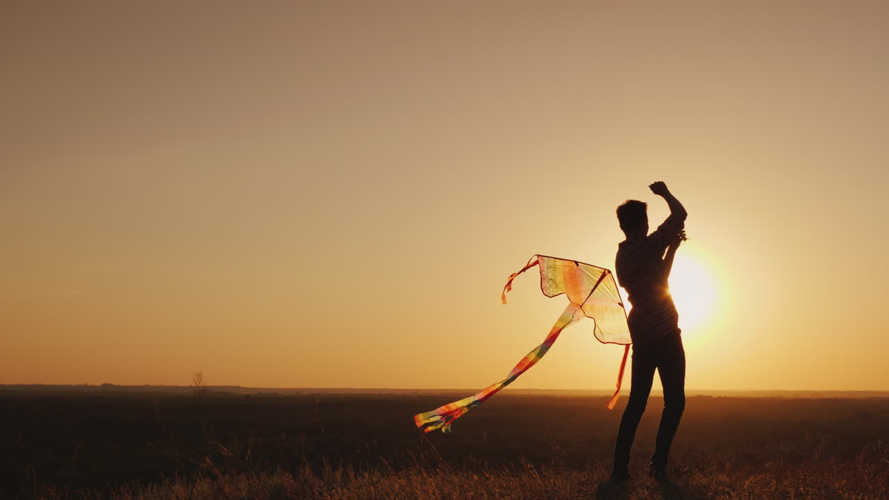 un adolescente lanza una cometa al atardecer video 4k
