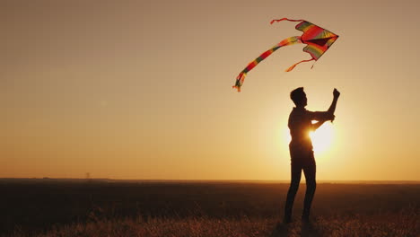 a teenager launches a kite at sunset 4k video