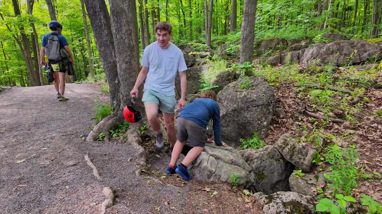 Three boys hiking and exploring on a forest trail at Rattlesnake Point, Ontario, Canada