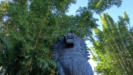 statue surrounded by bamboo and palm trees