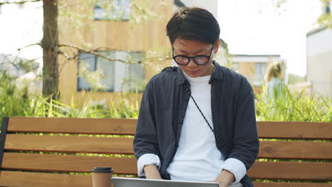 young asian woman working on laptop in park