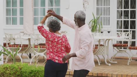 A-senior-African-american-couple-dancing-in-the-garden-in-social-distancing