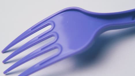 motion along violet disposable fork on white background