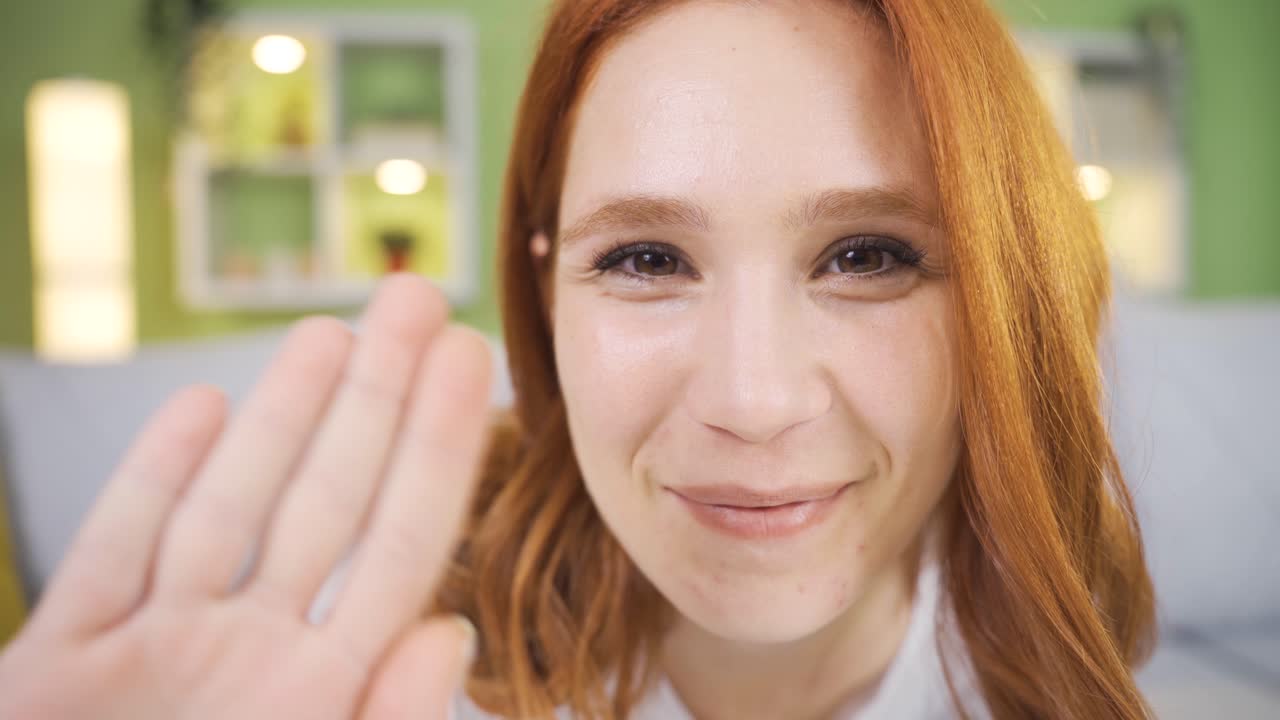 카메라를 향해 손을 흔드는 귀 ⁇ 고 장난스러운 젊은 여성의 클로즈업 초상화.