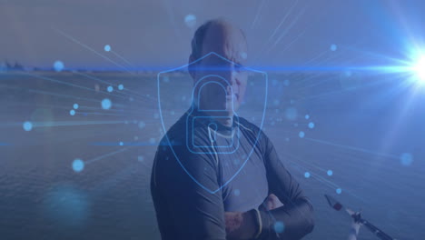 senior man standing arms crossed on dock by water, showing digital security shield padlock overlay