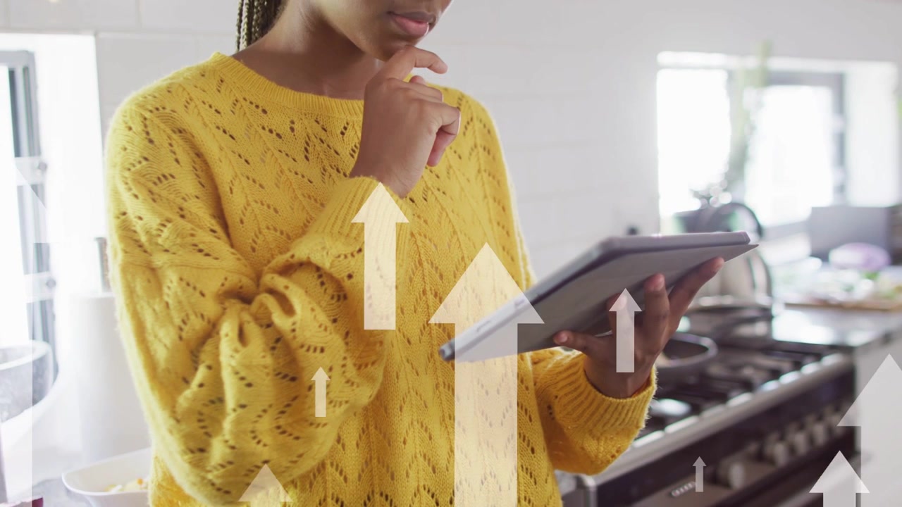 Woman tapping tablet causing up arrows over screen, pulling back revealing face reviewing finance