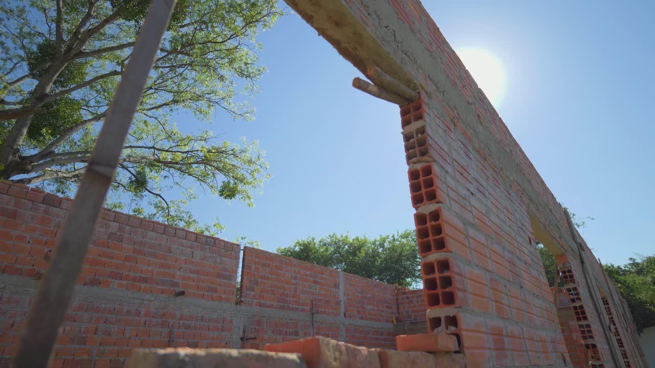 A brick wall with a window in it. The sun is shining through the window