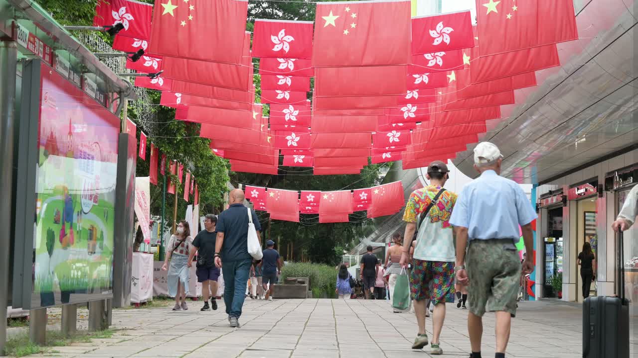 In Hong Kong, pedestrians stroll below the flags of China and the Hong Kong SAR, which are prominently hung overhead.