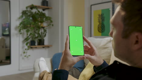 man watching smartphone with greenscreen, tracking markers, slow zoom in shot