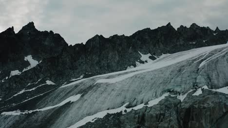 Alaskan-Rugged-Mountain-Range,-Drone-Flying-through-the-Clouds-and-Mountains-at-Sunrise