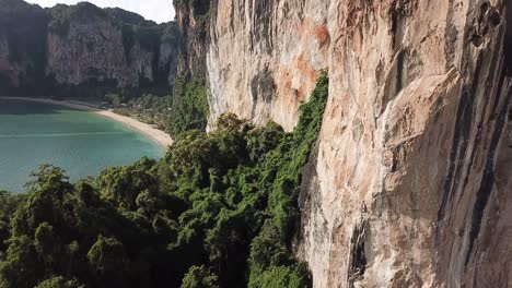 ascending drone aerial view on steep limestone cliffs over exotic railay beach, krabi thailand