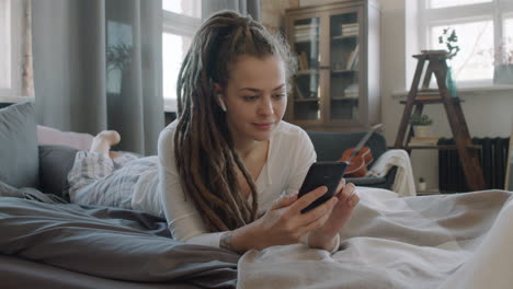 woman with smartphone chilling in bed