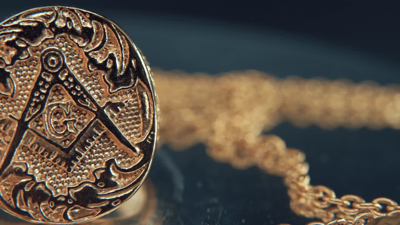 A macro detailed shot of a golden textured freemasons ring, on a mirror reflection stand, illuminati symbol, studio light, 4K video, pan right crane movement, masonry