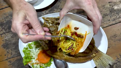 vertiendo salsa sobre el pescado con verduras