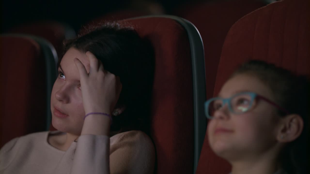 adolescente viendo una película en el cine con su hermana menor
