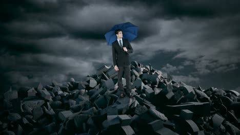 Businessman-with-umbrella-standing-on-debris-rocks-during-storm