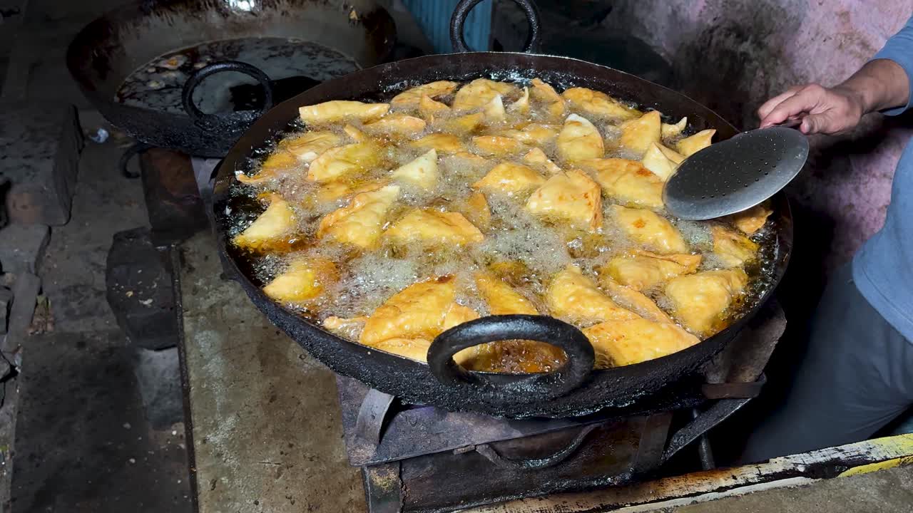 Samosa india tradicional friéndose en una sartén de hierro grande en un puesto callejero