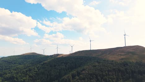 drone view capturing the movement of renewable energy turbines under a beautiful sky. mountains and nature offer a peaceful, sustainable backdrop