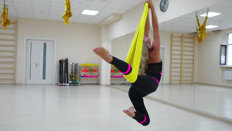 el concepto de deportes para un estilo de vida saludable. la niña ha sido la aerología de la antigravedad se relaja y se balancea en el lienzo en una habitación blanca. rotación en el lienzo alrededor de su eje