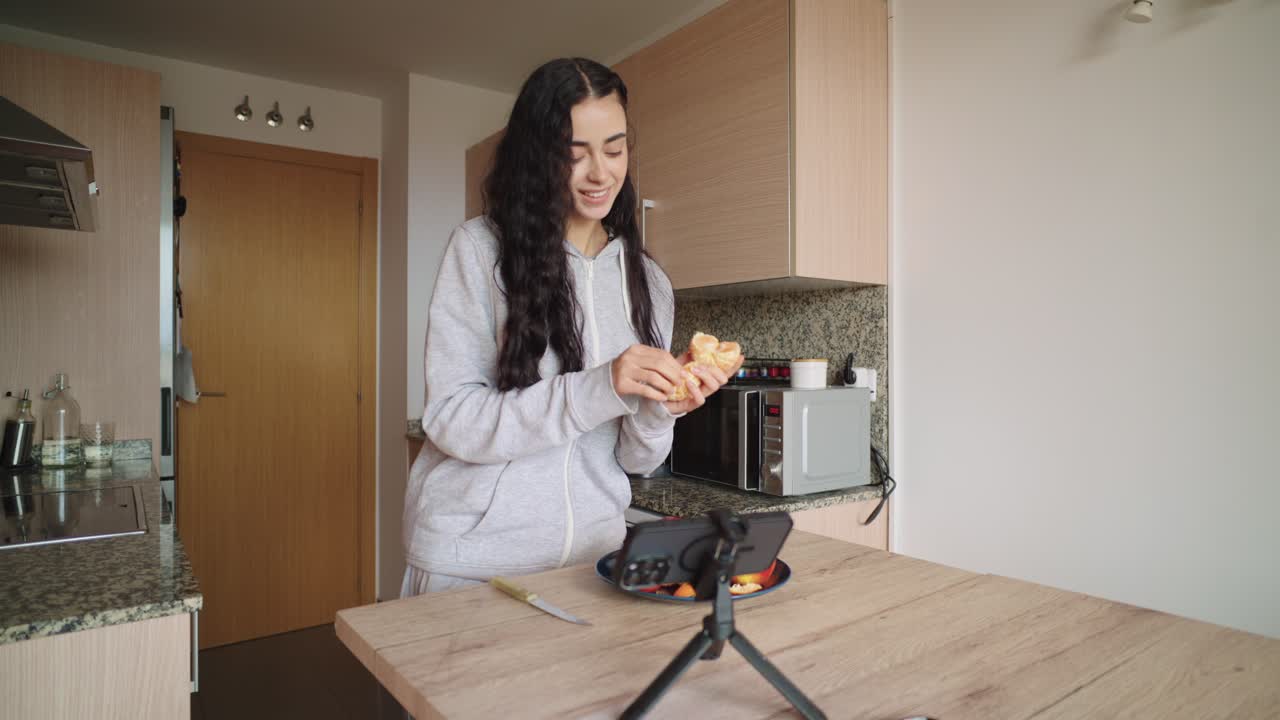 Woman preparing food in kitchen for mobile phone recording