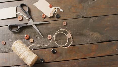 video of scissors, twine string, buttons and gift tags on dark wood boards with copy space