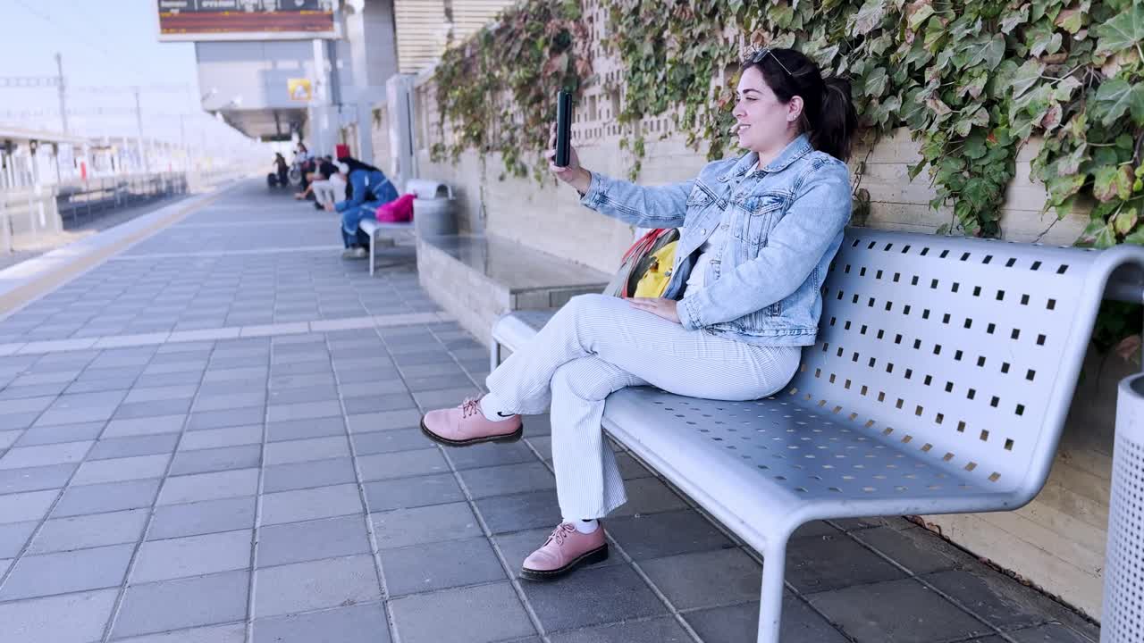 Giovane donna che scatta un selfie sul binario di una stazione ferroviaria