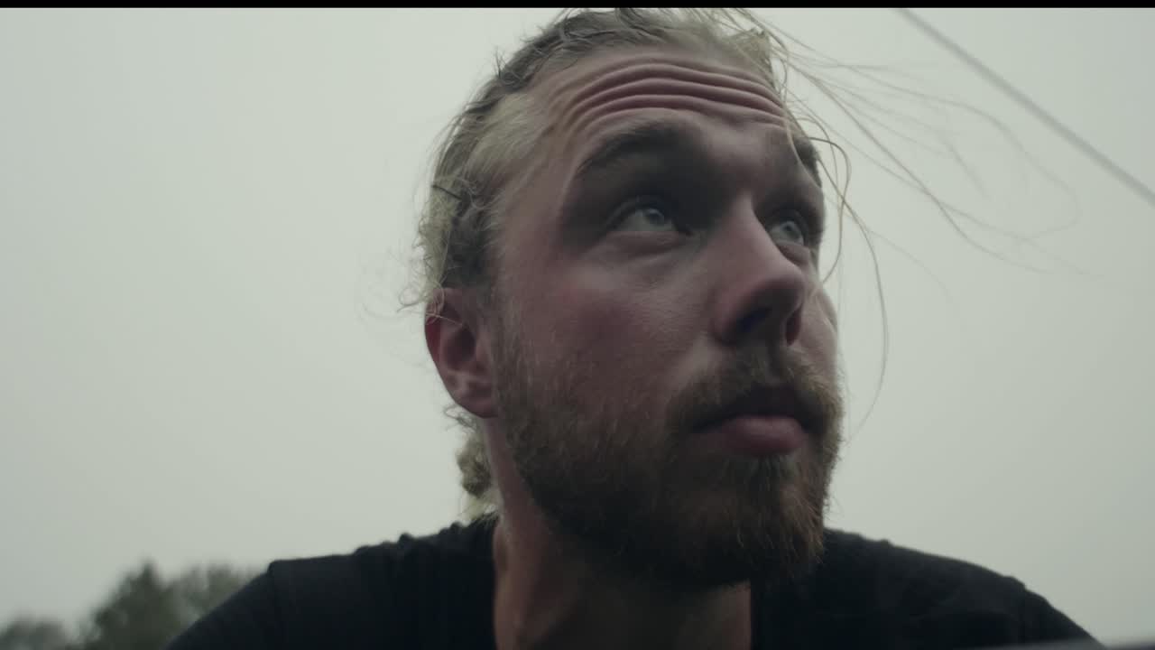 120 кадров в секунду - усталый и потный молодой кавказский мужчина с бородой и хвостиком смотрит на гору