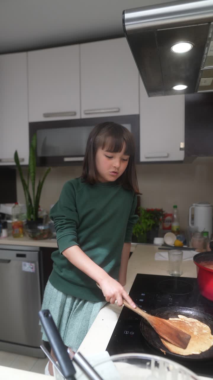 Young girl cooking pancakes in the kitchen