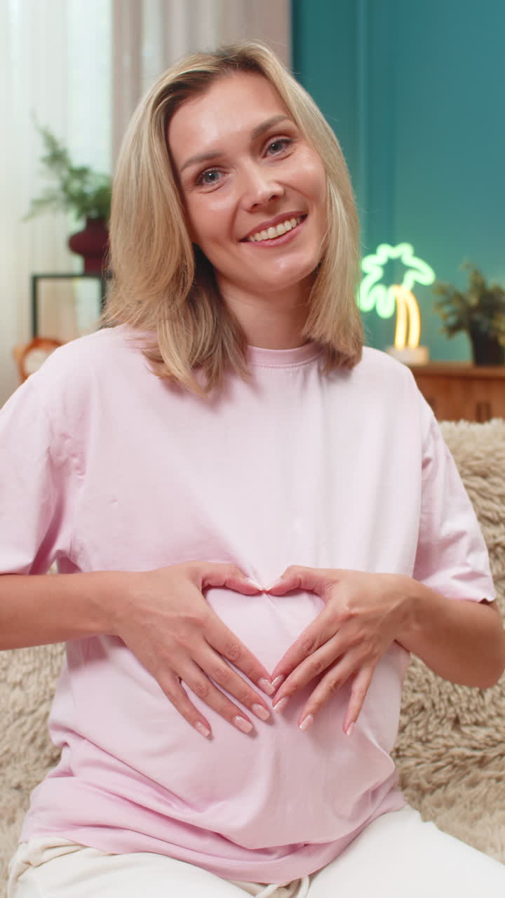 Mulher grávida formando um coração com as mãos sobre a barriga, sorrindo e desfrutando de um doce momento de amor antes do nascimento.