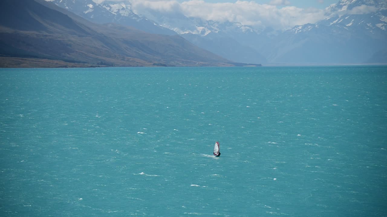 серфер, пересекающий озеро пукаки в солнечный день