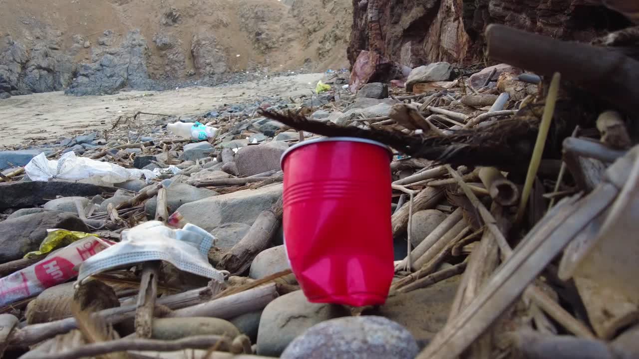 Plastic garbage and dirty waste on beach. disposable face mask and plastic cup. ecological pollution problem