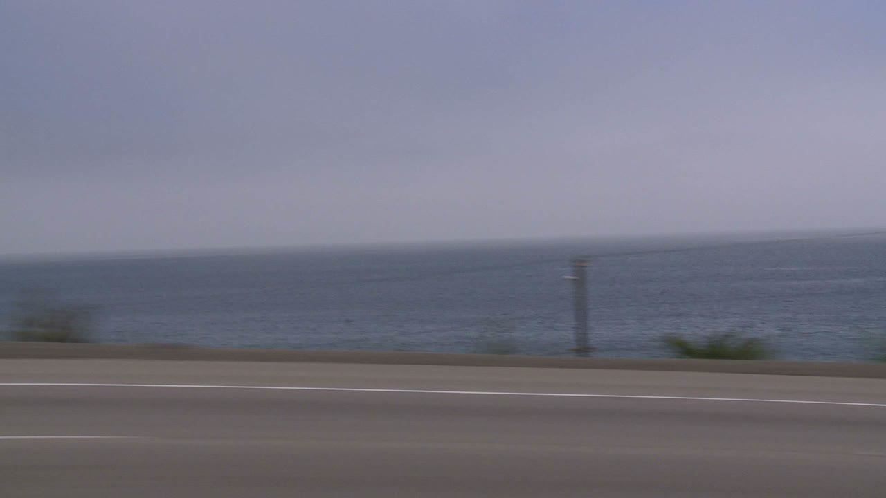 사이드 윈도우 3을 통해 보이는 태평양 연안 고속도로를 따라 자동차가 이동합니다.