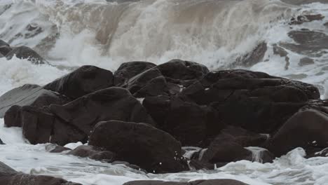 slow motion waves swirl in and surround well worn black rock of canada's stormy hudson bay