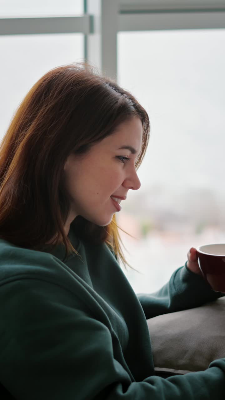 Kvinde slapper af på sofaen med kaffe