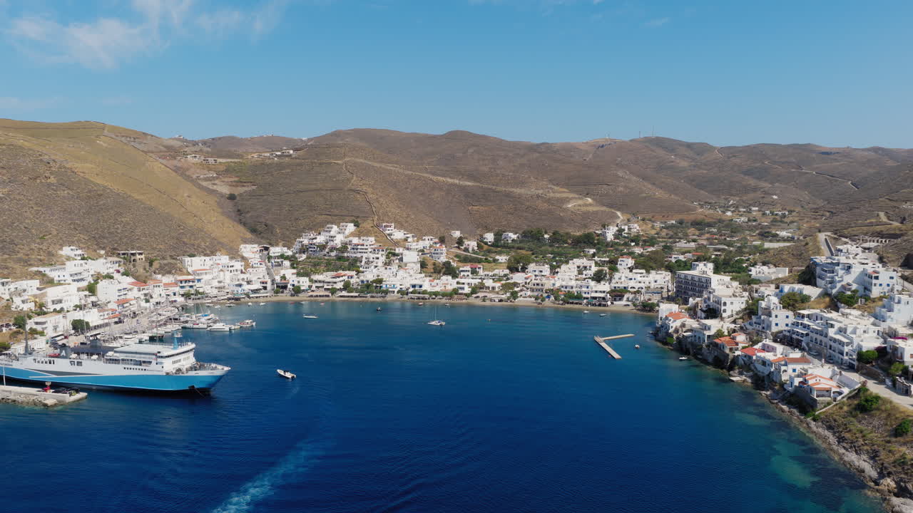 Aerial view of Merichas port and Gialos Beach in Kythnos, Greece, bustling with boats and beachgoers on a sunny summer day