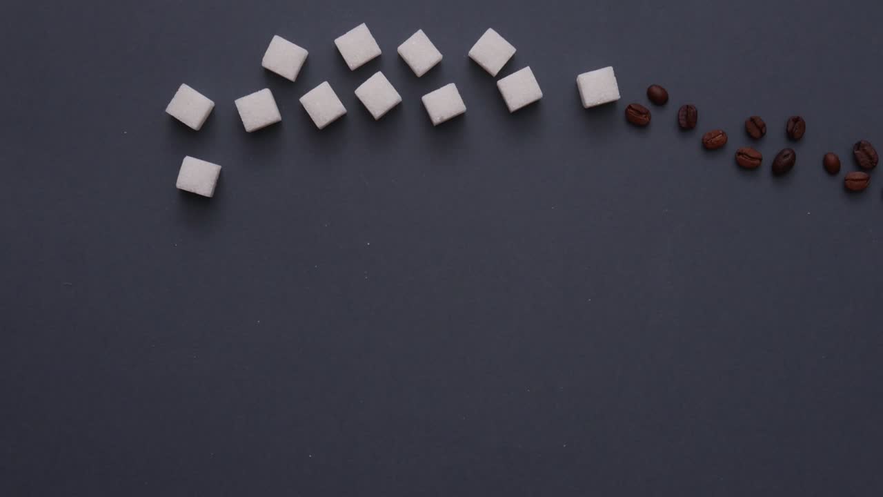 animación de stop motion de granos de café con cubos de azúcar en un fondo gris oscuro. concepto de comida y bebida. vista superior