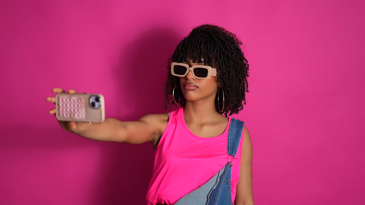 Woman taking a selfie with pink background